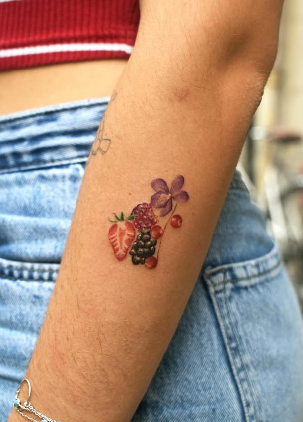 Tatouage de fraise, framboise, mûre, cerises et violette sur le bras