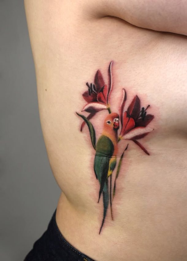 Tatouage d'un inséparable posé dans des lys rouges sur les côtes